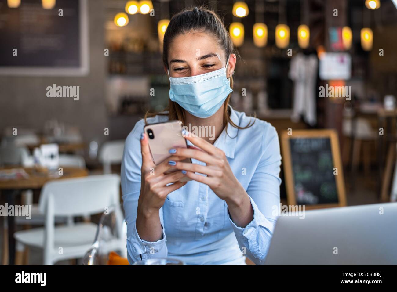 Portrait d'une jeune femme d'affaires, portant un masque tout en parlant sur un téléphone portable. Concept de nouveau mode de vie normal pendant la pandémie de Covid-19. Banque D'Images