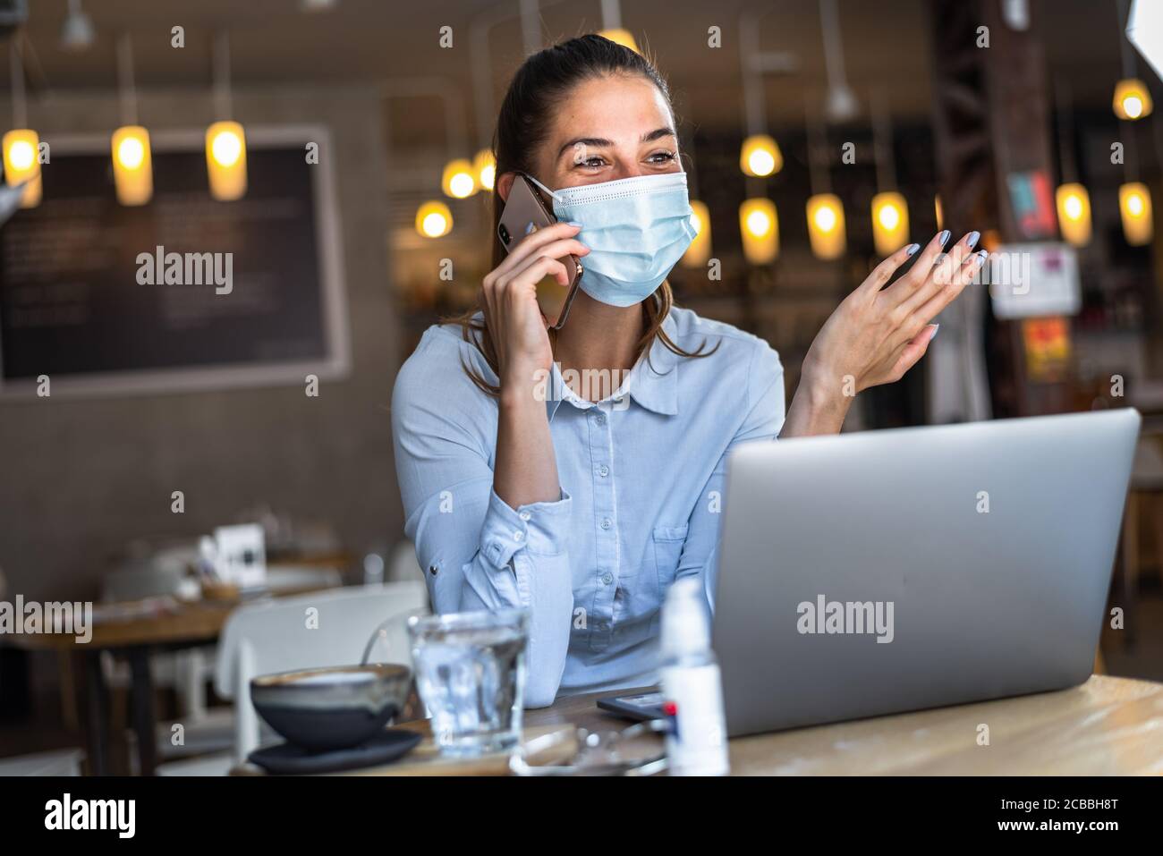 Portrait d'une jeune femme d'affaires, portant un masque tout en parlant sur un téléphone portable. Concept de nouveau mode de vie normal pendant la pandémie de Covid-19. Banque D'Images