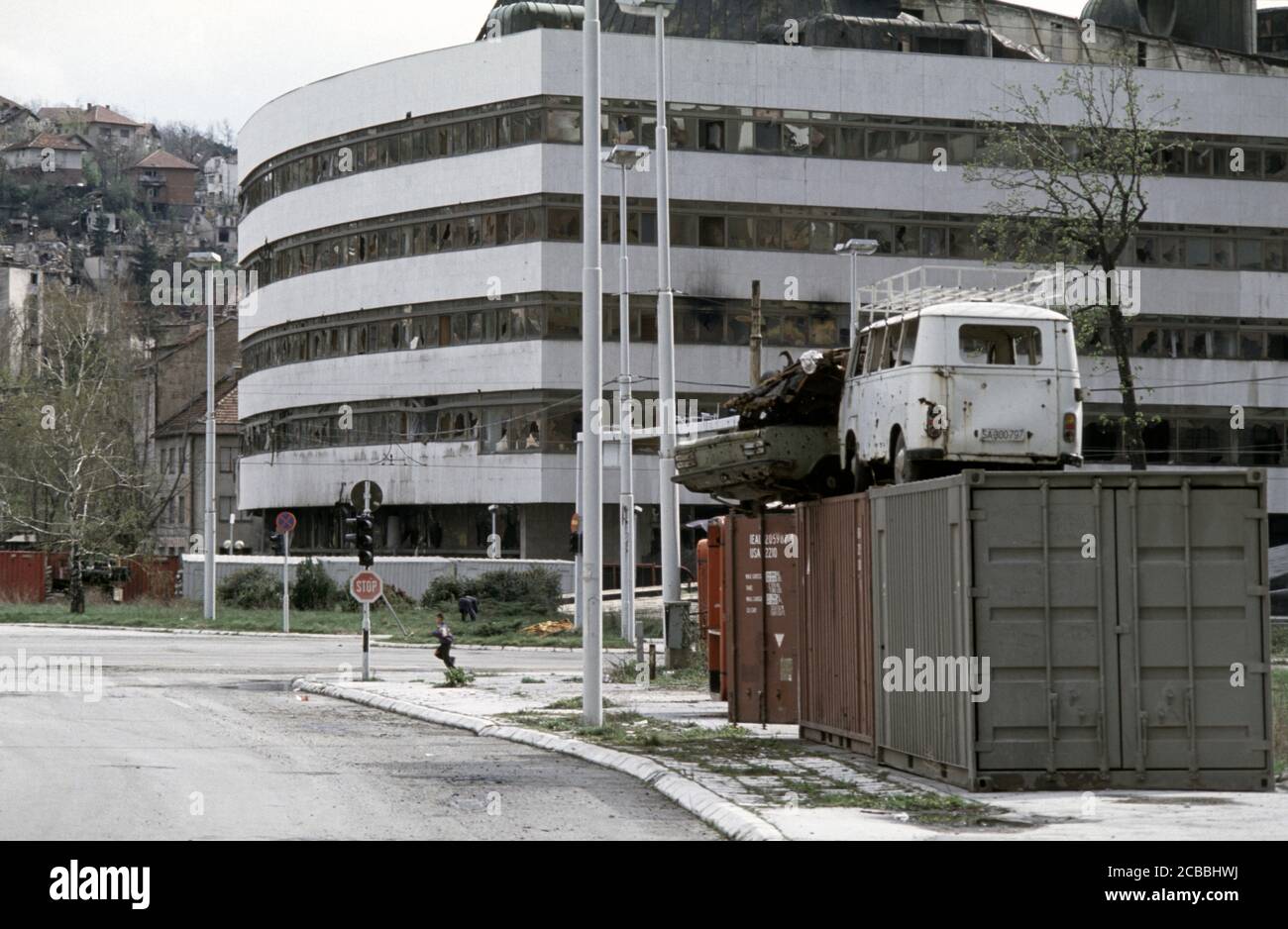 12 avril 1994 pendant le siège de Sarajevo : un jeune garçon déchègue un point d'accès de sniper à côté du bâtiment d'assemblage brûlé. Banque D'Images