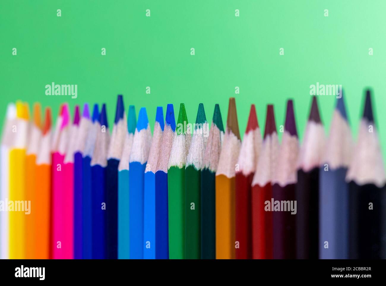 gros plan des crayons de couleur alignés verticalement avec un arrière-plan vert Banque D'Images