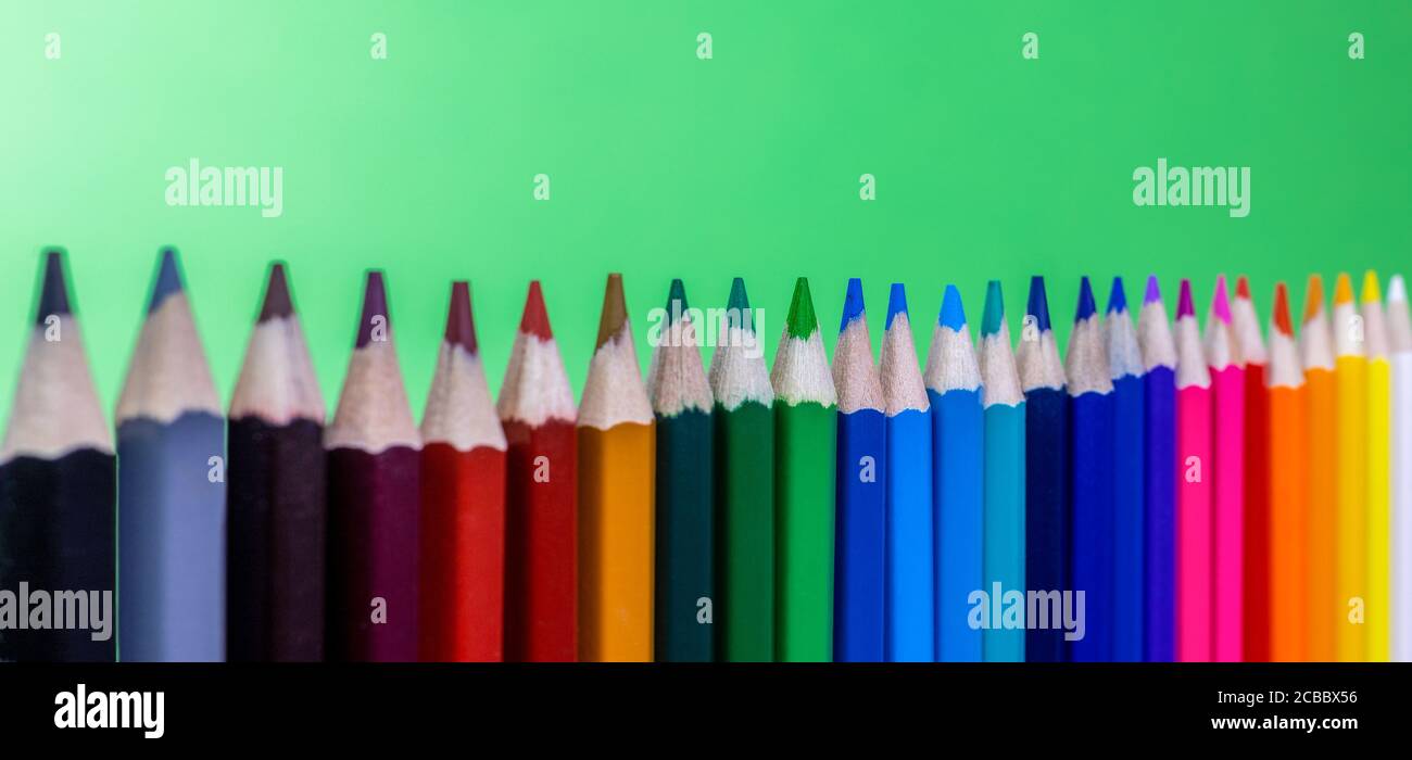 gros plan des crayons de couleur alignés verticalement avec l'arrière-plan vert, panorama Banque D'Images