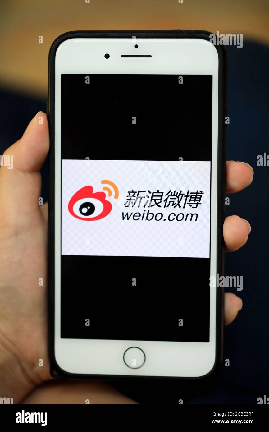 Une main tenant un iPhone avec le logo de Sina Weibo/Weibo Une plate-forme chinoise de microblogging sur les médias sociaux à l'écran Banque D'Images