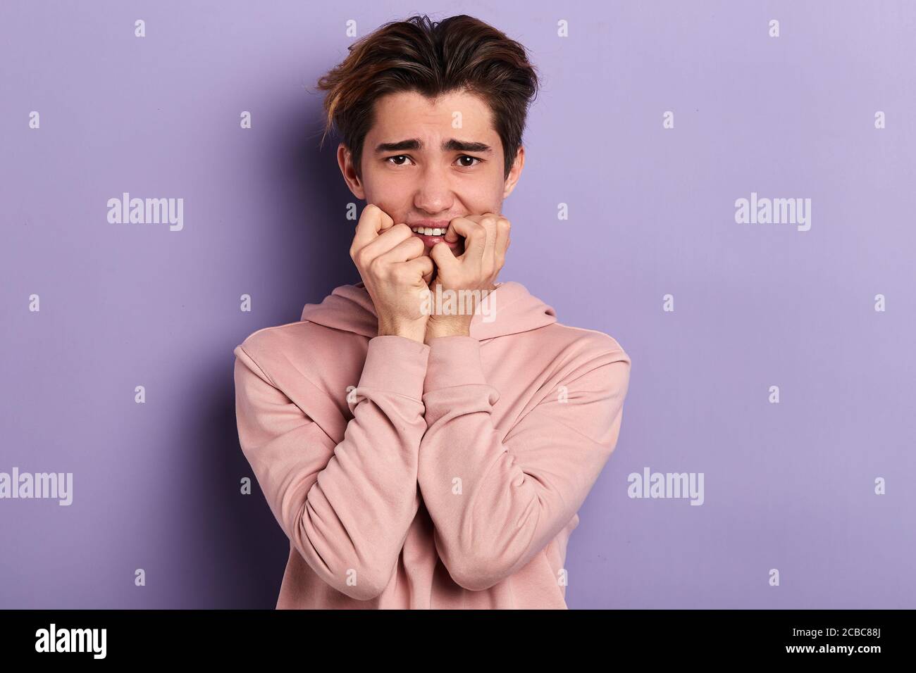 un élève nerveux piquant ses ongles, attendant les résultats des examens. gros plan photo. arrière-plan bleu isolé, prise en studio Banque D'Images