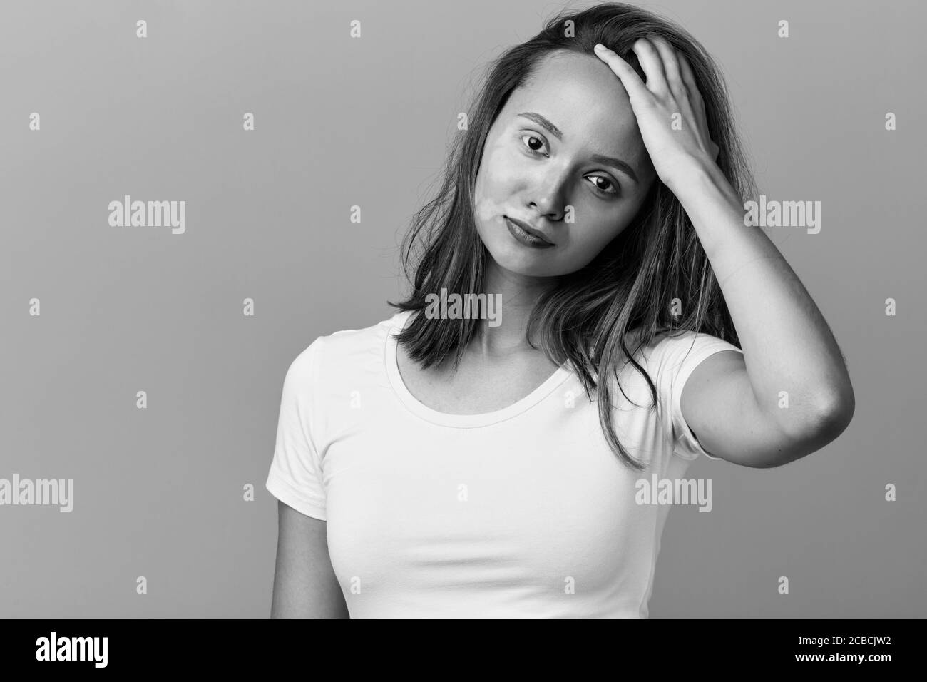 belle fille impressionnante touchant son front. elle pense aux problèmes de peau, à la résolution des problèmes. photo noir et blanc. portrait gros plan. noir isolé Banque D'Images