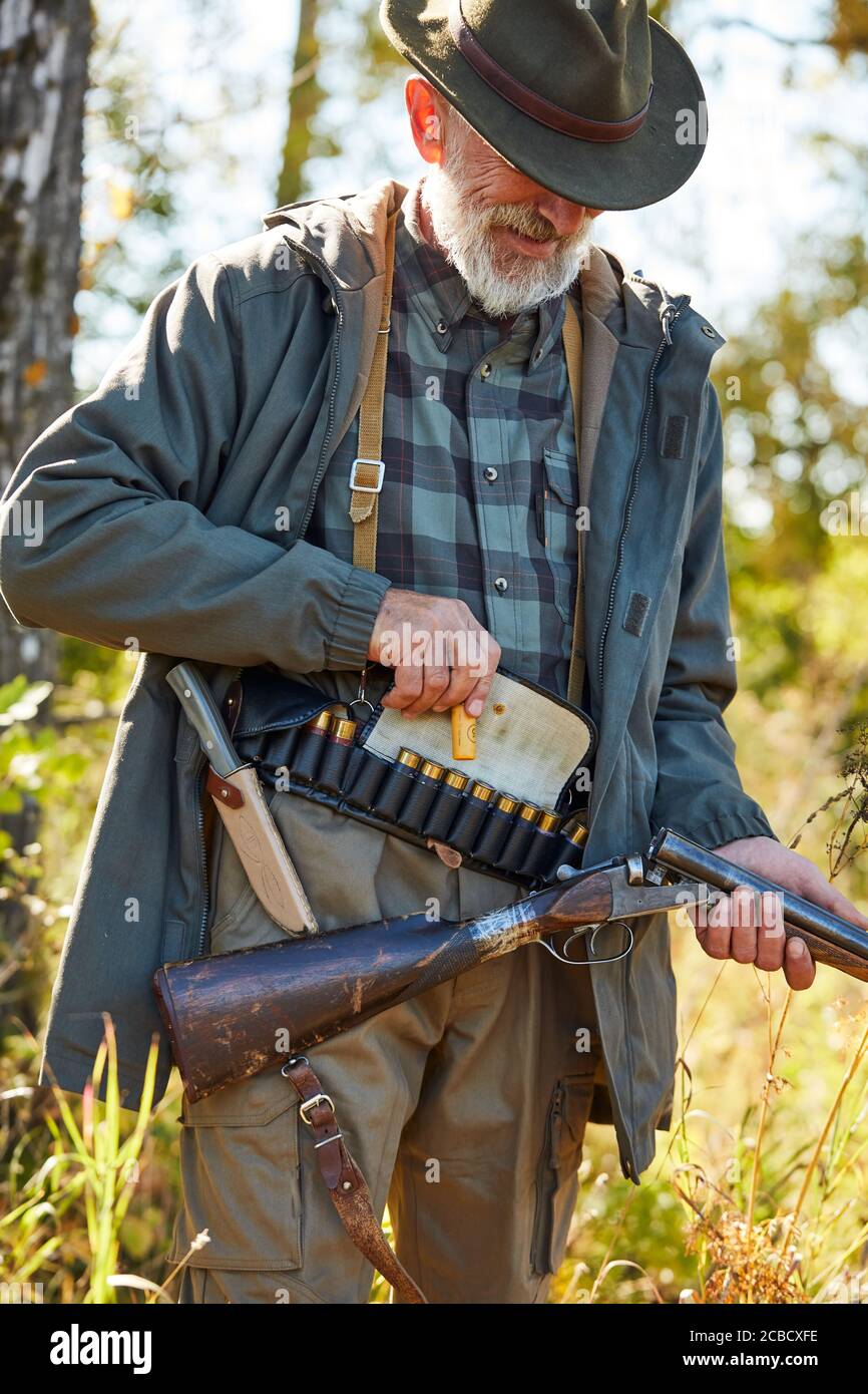 Fowler tenant le fusil de chasse, les cartouches sur le bas du dos, prêt à tirer sur les oiseaux. Arrière-plan de la forêt Banque D'Images