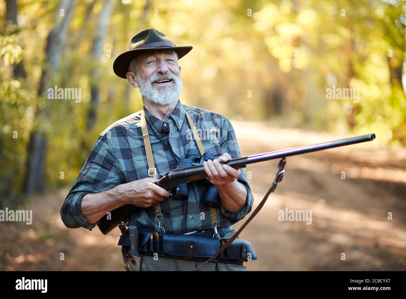 Homme gai avec le fusil de retenue avec les deux bras, rire. Saison de chasse ouverte, en forêt Banque D'Images
