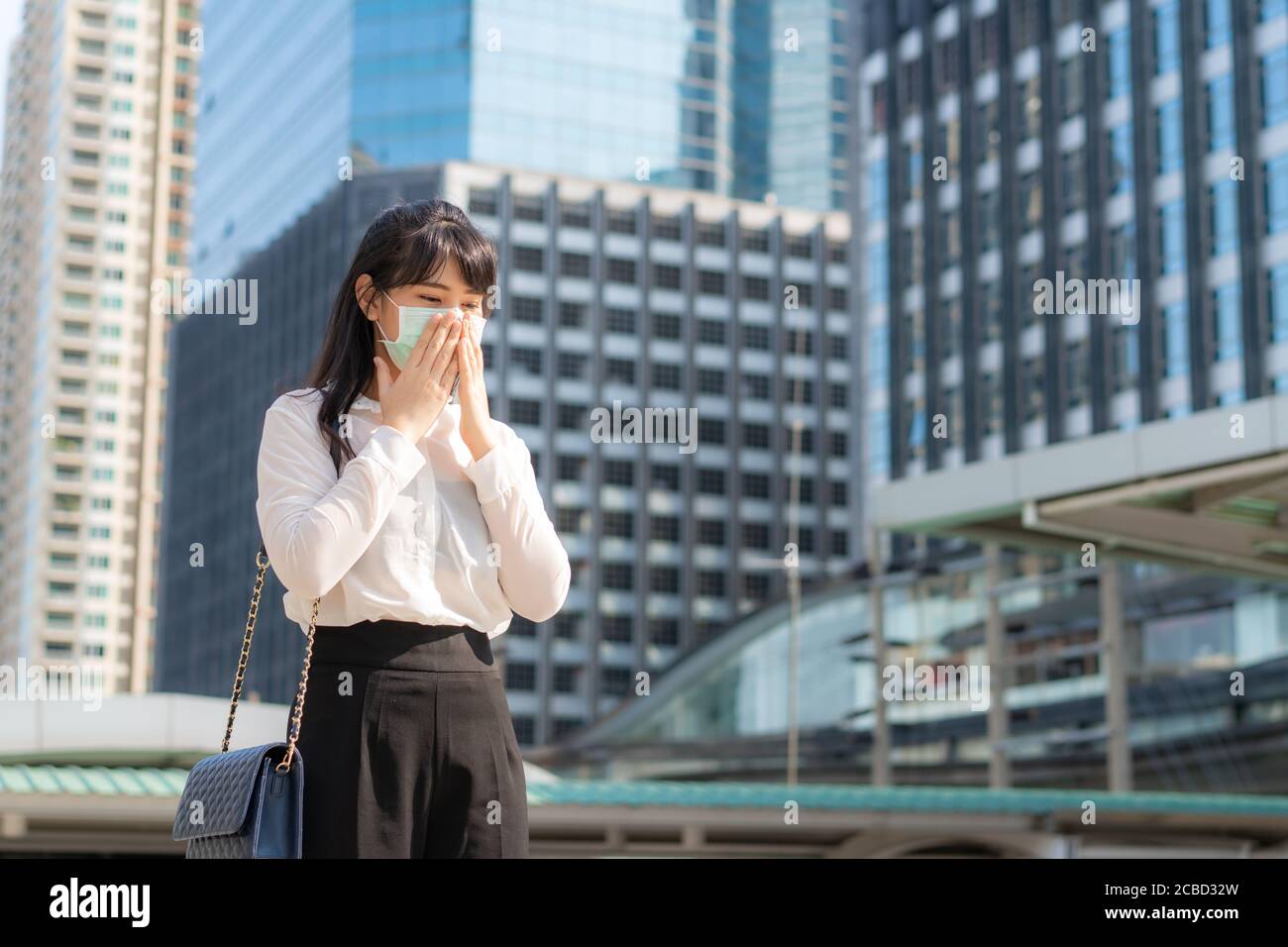 La jeune femme d'affaires asiatique en chemise blanche qui va travailler malade avec la toux porte un masque de protection pour éviter la poussière, le smog, la pollution de l'air et le COVID de PM2,5 Banque D'Images