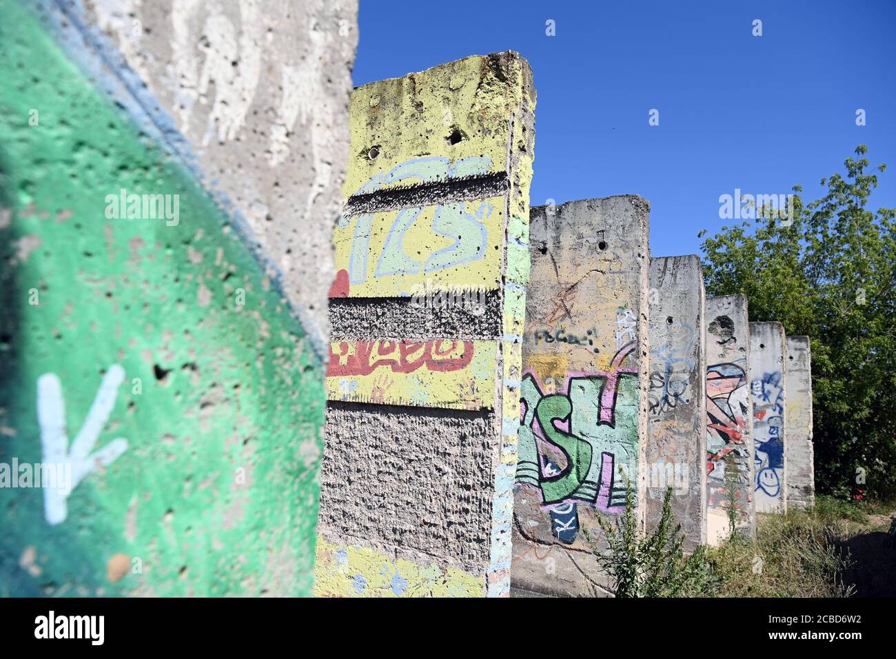 Teltow, Allemagne. 12 août 2020. Des pièces peintes ou pulvérisées du mur de Berlin sont situées sur un site industriel près du bassin du port, sur le canal de Teltow. Au début des années 1990, une entreprise de construction de l'Armée populaire nationale a acheté les pièces murales. Des artistes et des profanes ont peint les parties en béton. Environ quarante des 170 parties qui ont autrefois constitué le mur sont maintenant restées. Credit: Soeren Stache/dpa-Zentralbild/ZB/dpa/Alay Live News Banque D'Images