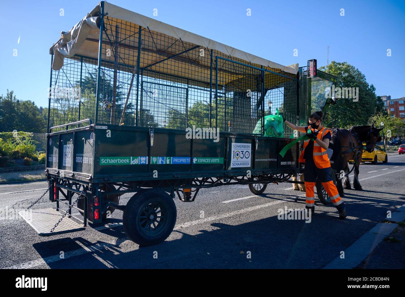 07 août 2020, Belgique, Brüssel: Kani de Muynck, étudiant, charge des sacs à ordures dans le wagon tiré par des chevaux du service de nettoyage dans le quartier Schaerbeek de Bruxelles. Depuis 2011, le service de collecte des déchets arrive six jours par semaine, non seulement avec les camions conventionnels, mais aussi à cheval et à chariot. Environ 200 poubelles publiques par jour sont ensuite vidées de cette façon. (À dpa 'camion de déchets avec sabots - amis à quatre pattes en action dans les rues de Bruxelles') photo: Sven Braun/dpa Banque D'Images