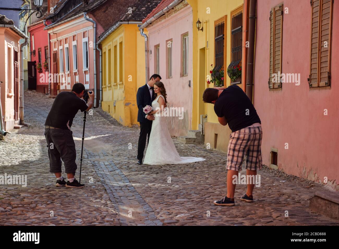 Sighisoara / Roumanie - 26 août 2019 : couple de mariage prenant des photos de mariage avec des photographes professionnels dans les rues historiques colorées de Sighisoara Banque D'Images