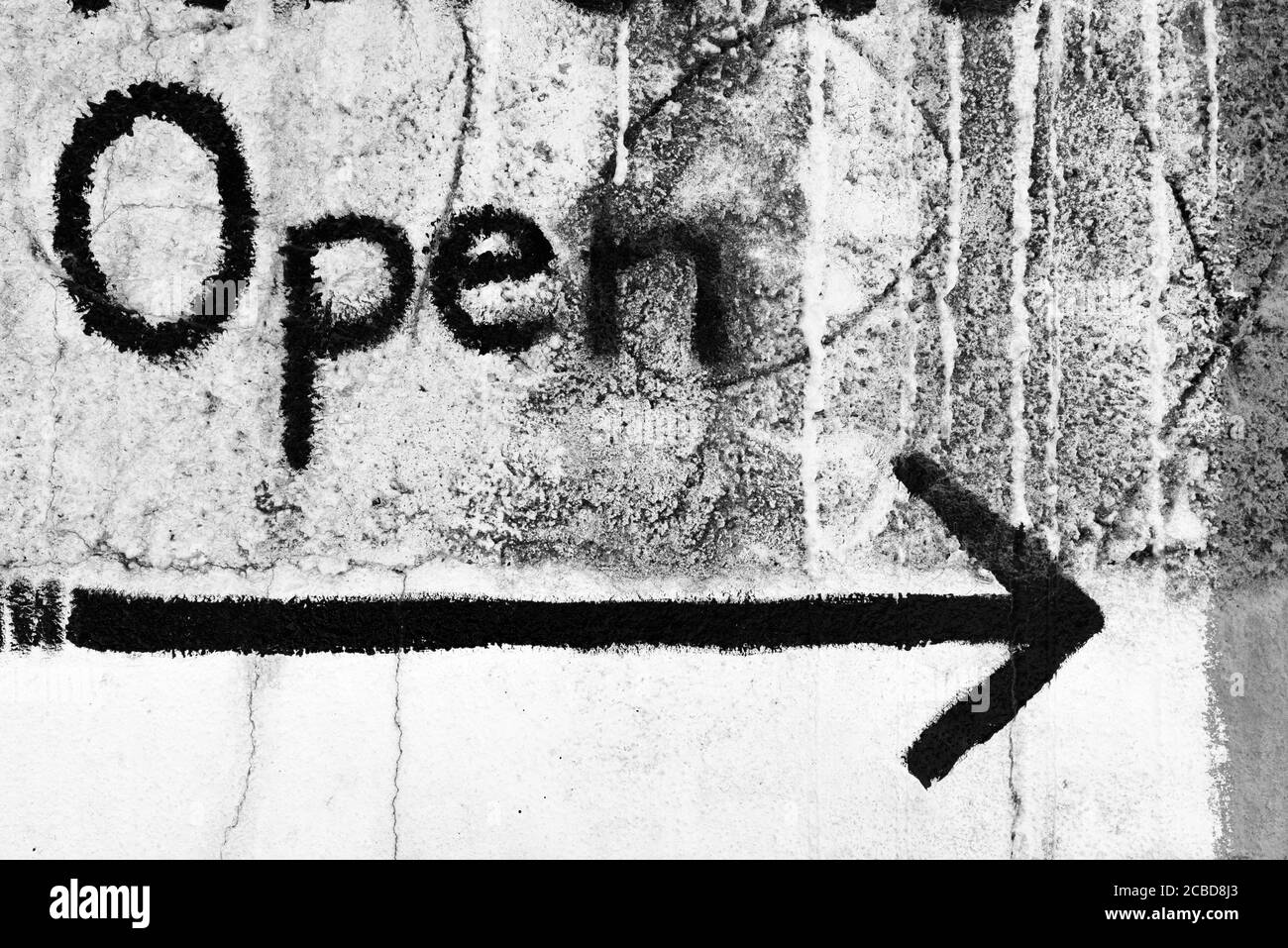 Image en noir et blanc de texte ouvert avec flèche pointant sur un mur sale Banque D'Images