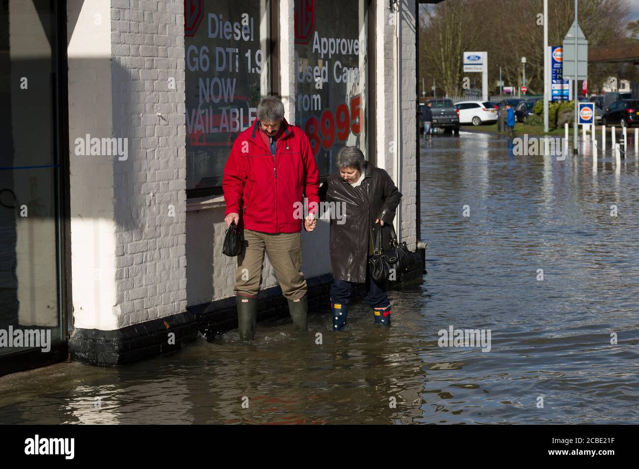 Un homme et une femme qui se sont emparées des eaux d'inondation sur la route de Slough dans le village de Datchet, dans le Berkshire, après que la Tamise ait éclaté ses rives. Datchet, Berkshire, Royaume-Uni. 10 févr. 2014 Banque D'Images