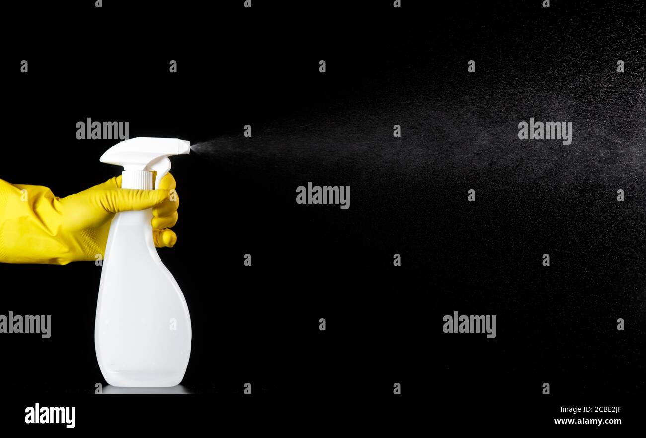 nettoyant ménager, aérosol blanc dans les mains avec des gants en caoutchouc jaune. Banque D'Images