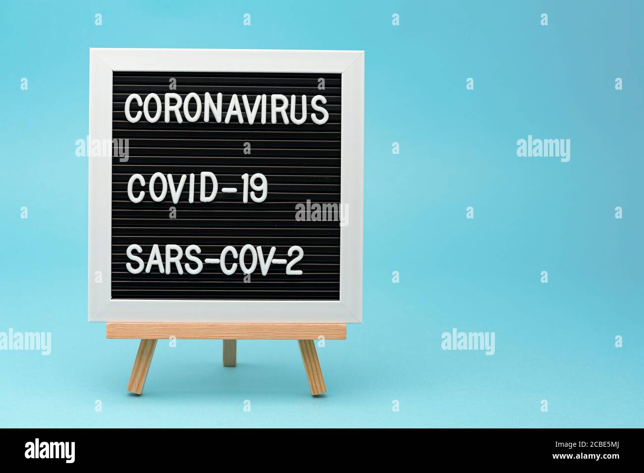 Tableau d'écriture : CORONAVIRUS, COVID-19 et SRAS-COV-2. Isolé sur fond bleu. Copier l'espace. Tir horizontal. Banque D'Images