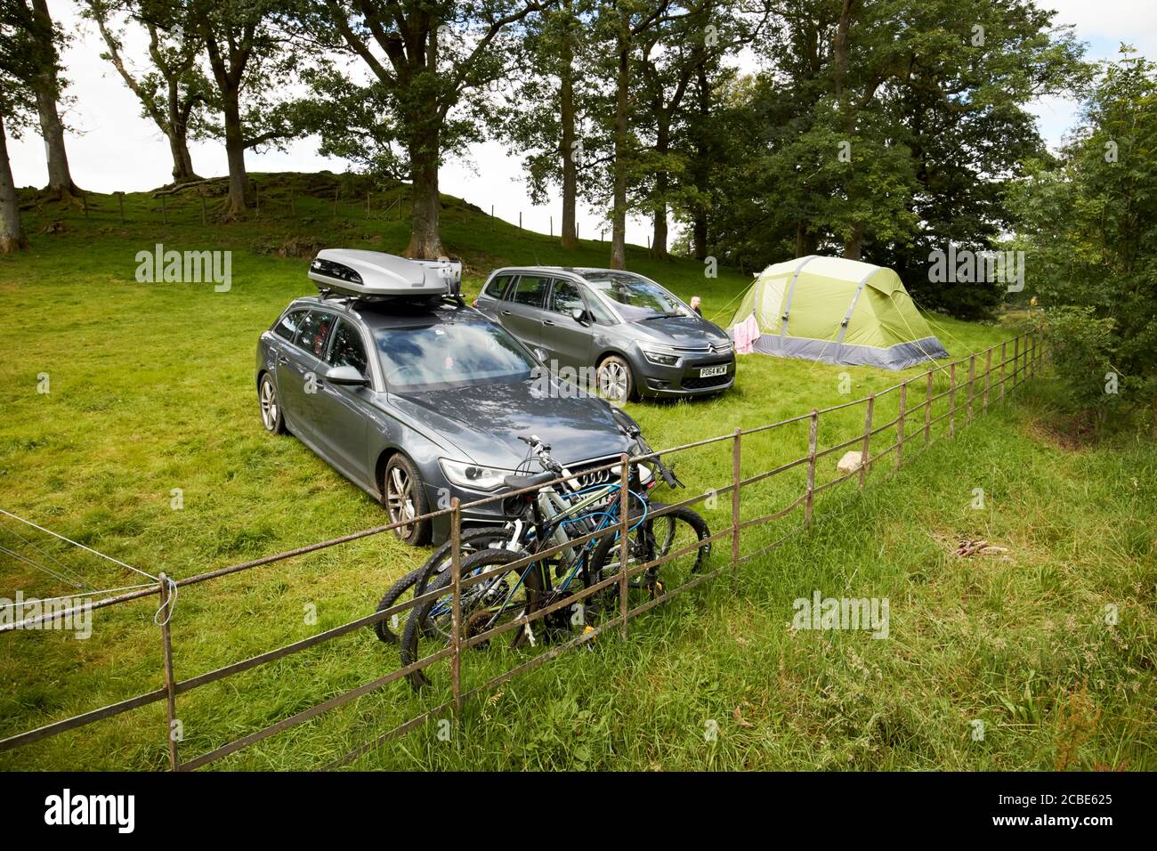 voitures garées dans un champ avec tente en camping avec les gens campent près de loughrigg lake district cumbria angleterre royaume-uni Banque D'Images