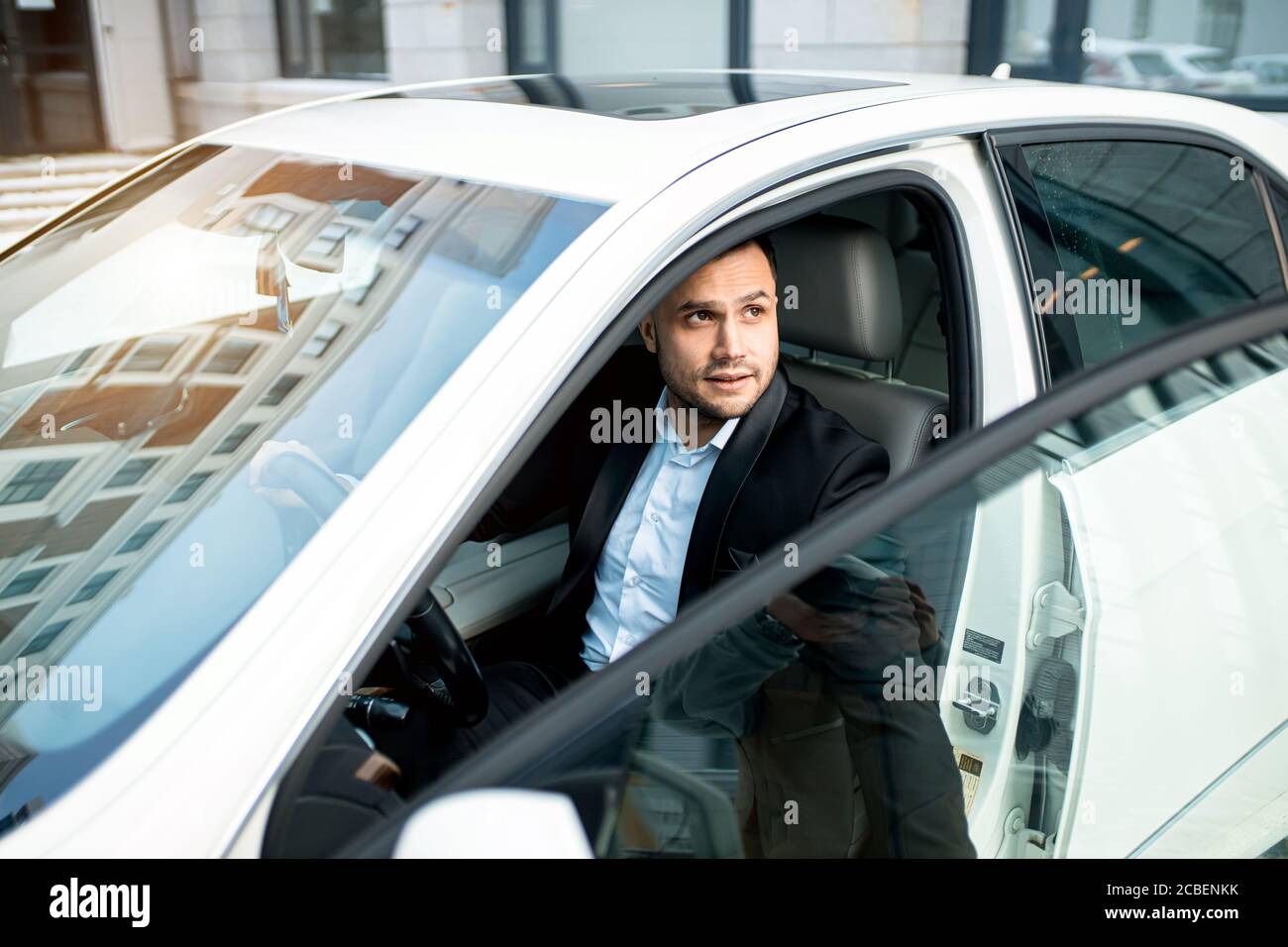 un jeune homme d'affaires qui a l'air de fermer la porte de sa voiture de  prestige, qui se tourne vers le haut. white new car, transport, concept  automobile Photo Stock - Alamy