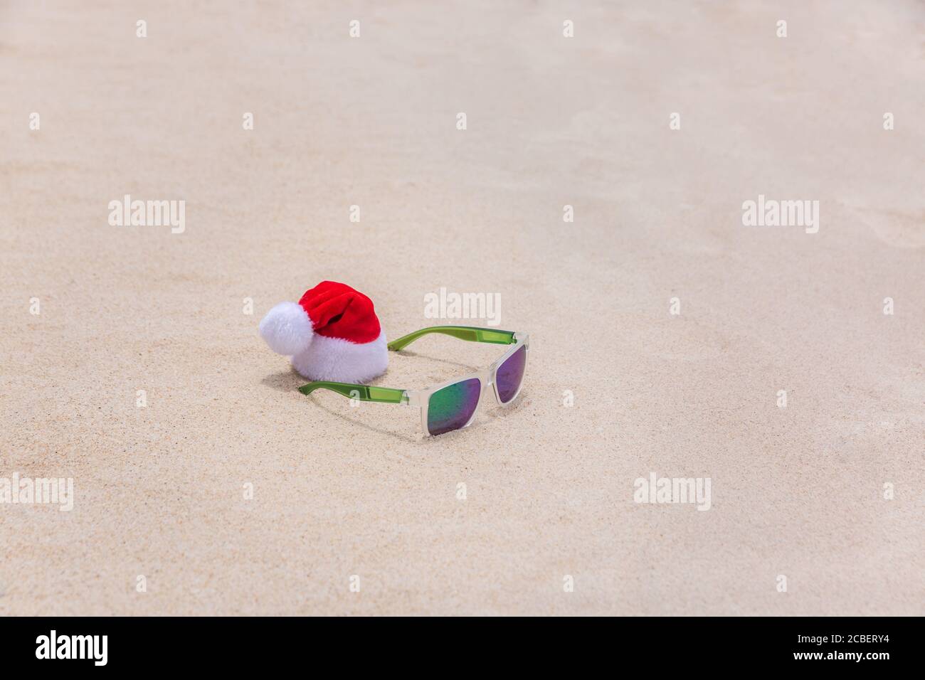 Chapeau de Noël avec lunettes de soleil dans le sable sur une plage tropicale. Concept été tropique de vacances Banque D'Images