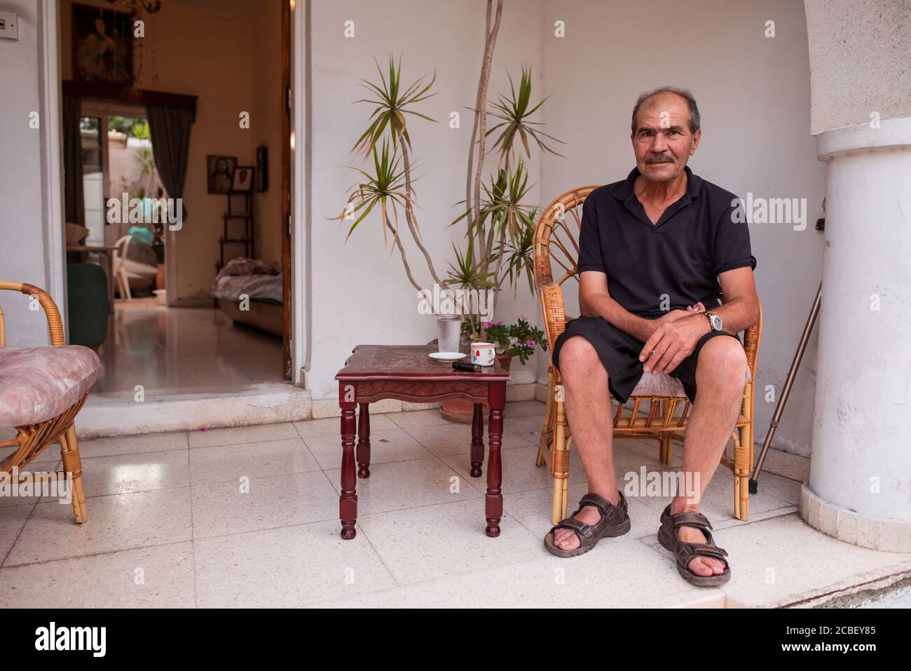 Larnaca / Chypre - 15 août 2019 : portrait d'un homme chypriote senior souriant assis sur le porche de sa maison Banque D'Images