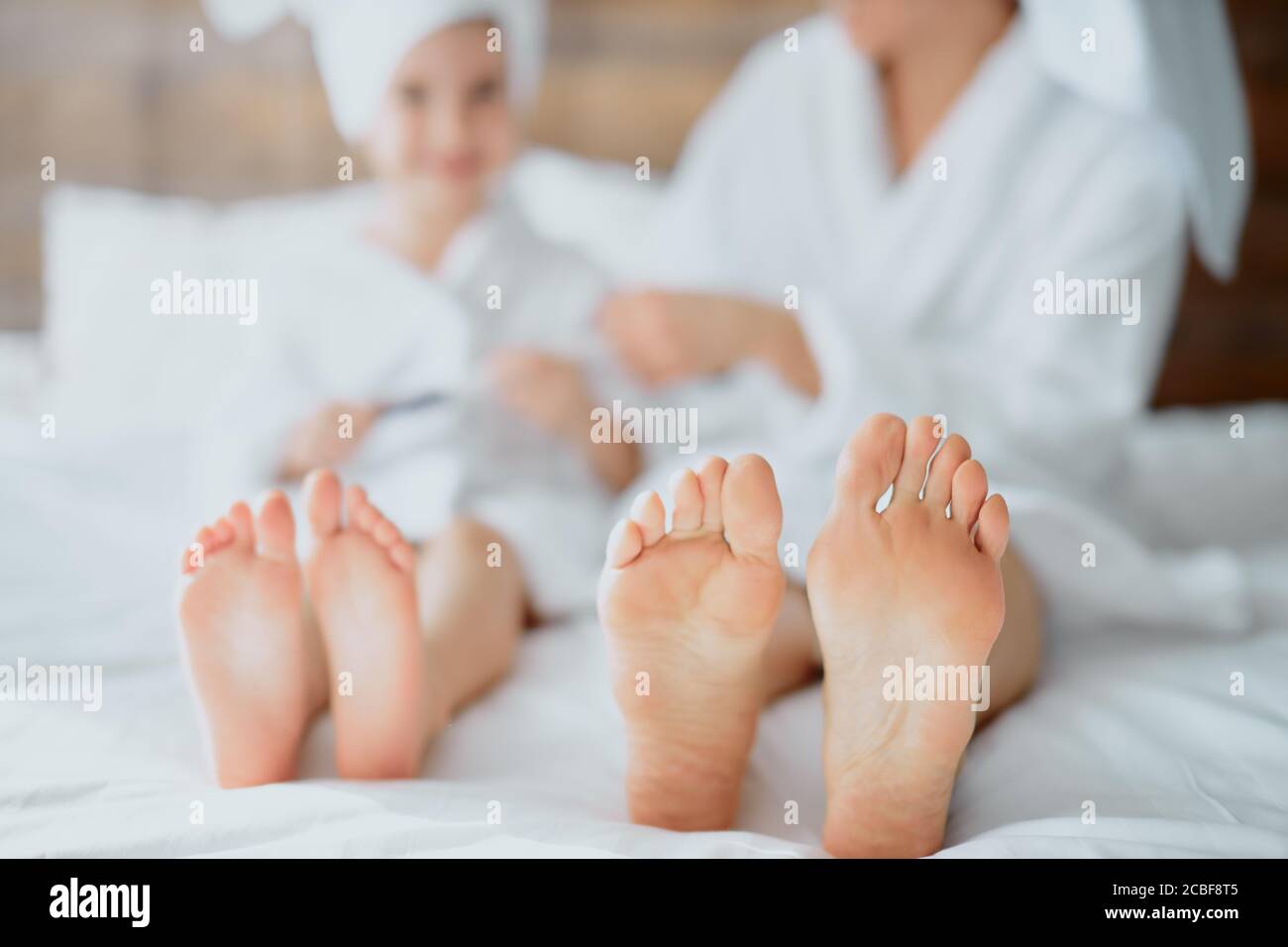 femme et enfant allongé sur un lit blanc portant des jambes peignoir et serviette Banque D'Images