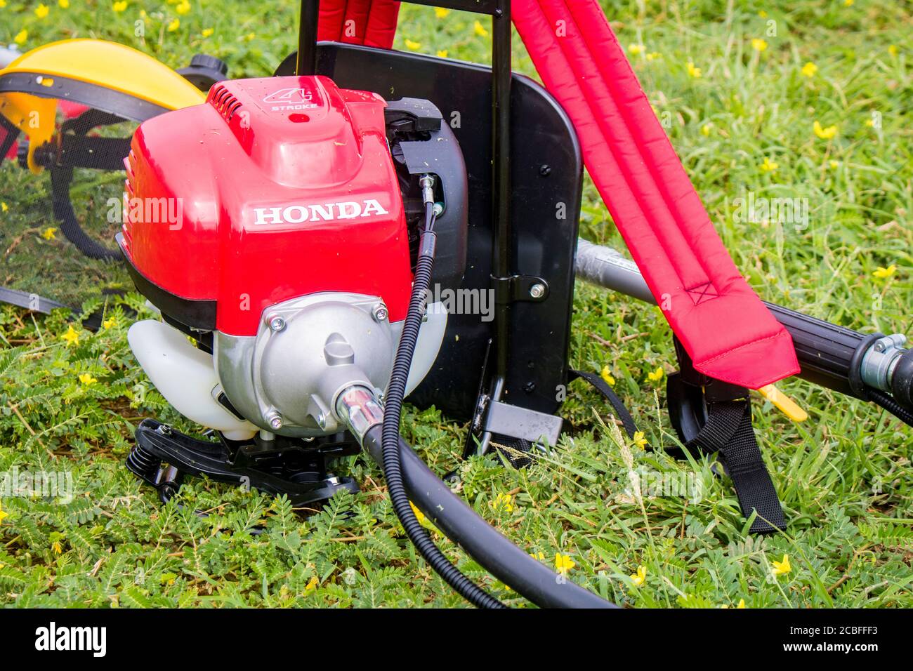 Un coupe-herbe Honda rouge, modèle UMR 435t, et un masque de sécurité jaune  sont au sol rempli de mauvaises herbes après le travail. Hua Hin, Thaïlande  Photo Stock - Alamy