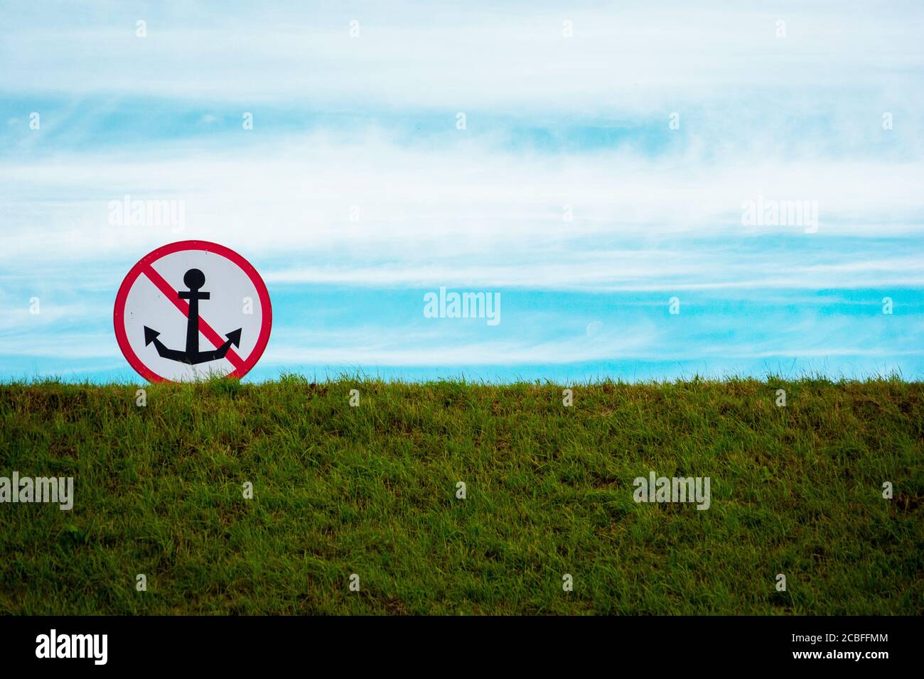 Panneau pour les bateaux 'Don't Drop Anchor' contre le ciel bleu, sur une colline herbeuse au bord de la mer. Photo en paysage avec un espace libre pour votre texte Banque D'Images