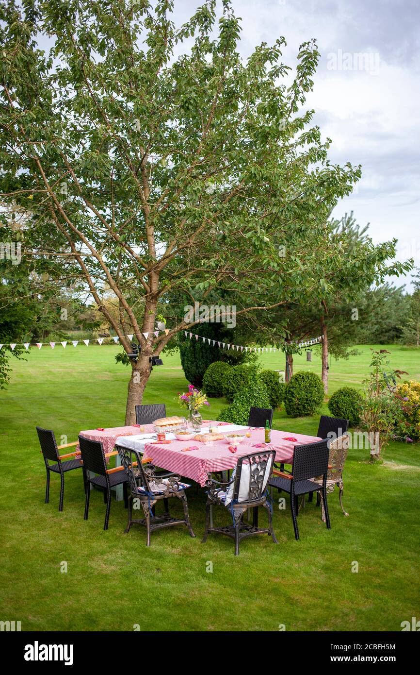 Table et chaises pour une fête d'été en plein air dans un grand jardin avec arbres et arbustes. Rufford, Lancashire Banque D'Images