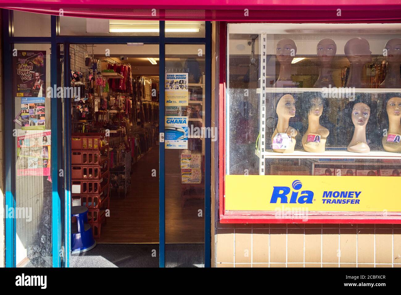 Une boutique d'accessoires de cheveux en Rugby avec perruques dans le Fenêtre et logo de transfert d'argent de Ria Banque D'Images
