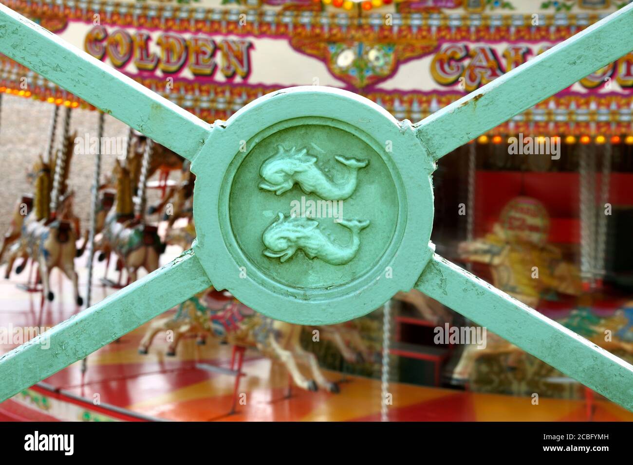 Gros plan sur les chemins de fer de la promenade de Brighton, avec les dauphins de l'écusson de la ville. Arrière-plan: joyeux-Go-round sur la plage. Banque D'Images