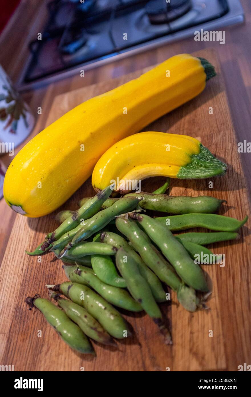 Courgettes jaunes surcultivées et larges cosses de haricots provenant de l'allotissement à la maison sur une planche à découper en bois Banque D'Images