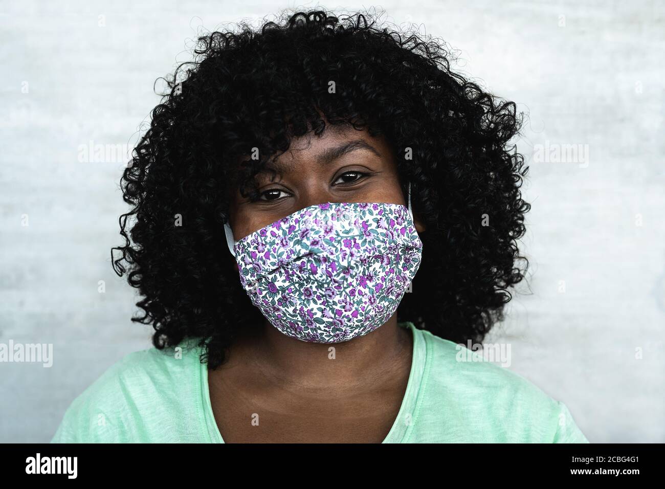 Portrait d'une femme africaine heureuse - fille afro portant un visage protecteur masque pour prévenir la propagation du virus corona Banque D'Images