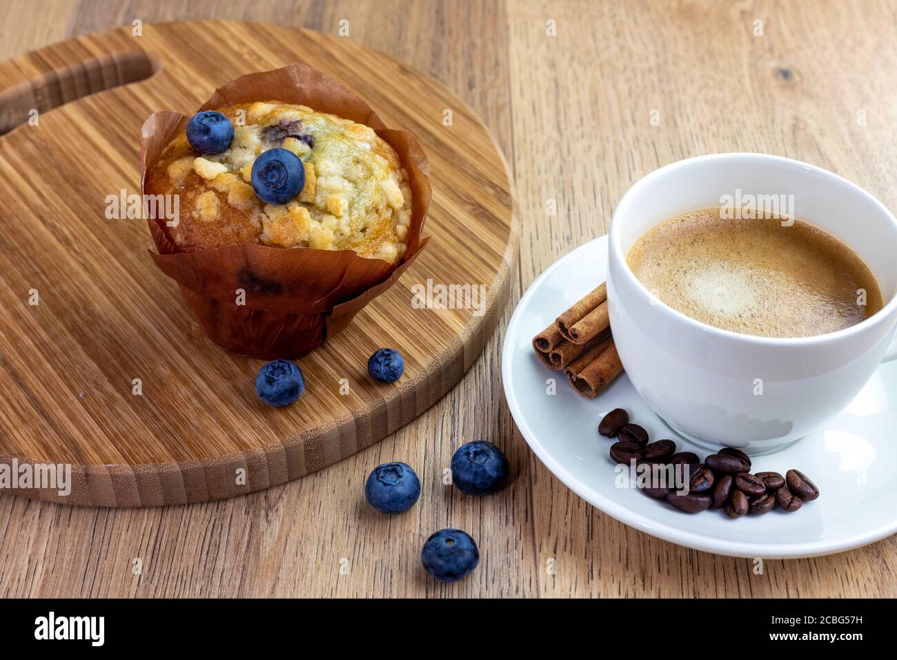 muffin aux myrtilles avec une tasse de café à la cannelle sur une table en bois Banque D'Images