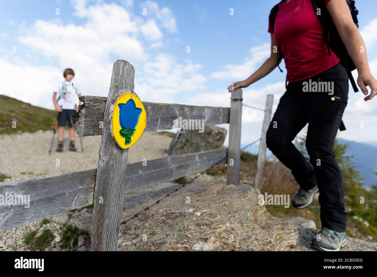 Mère grimpant au-dessus d'un Stile de pas, fils l'attendant, sentier d'amour, Granattor, croix de sommet, Lammersdorf montagne, Nock montagnes, Carinthie, Autriche Banque D'Images