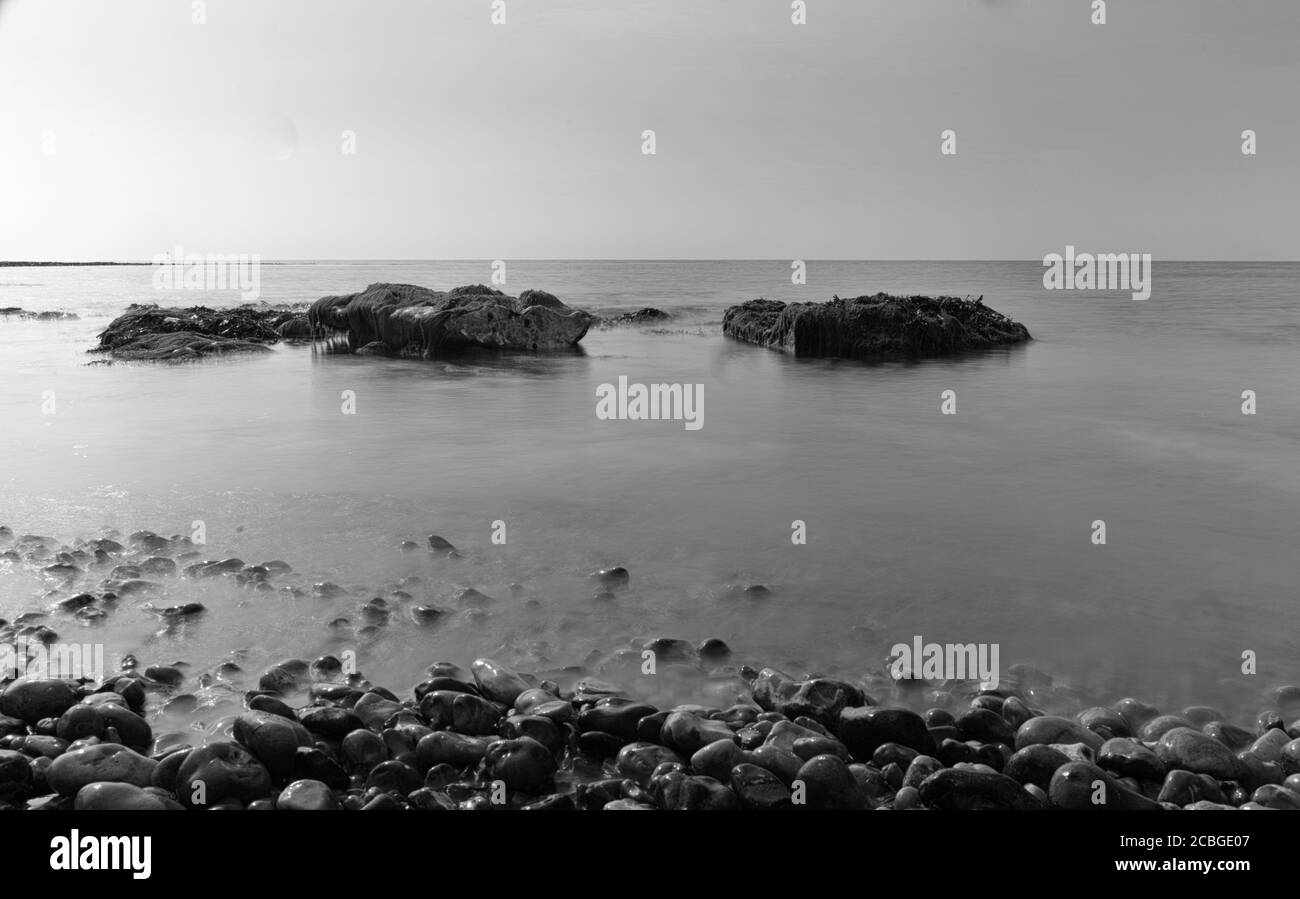 Rochers et galets exposés par une marée basse calme Banque D'Images