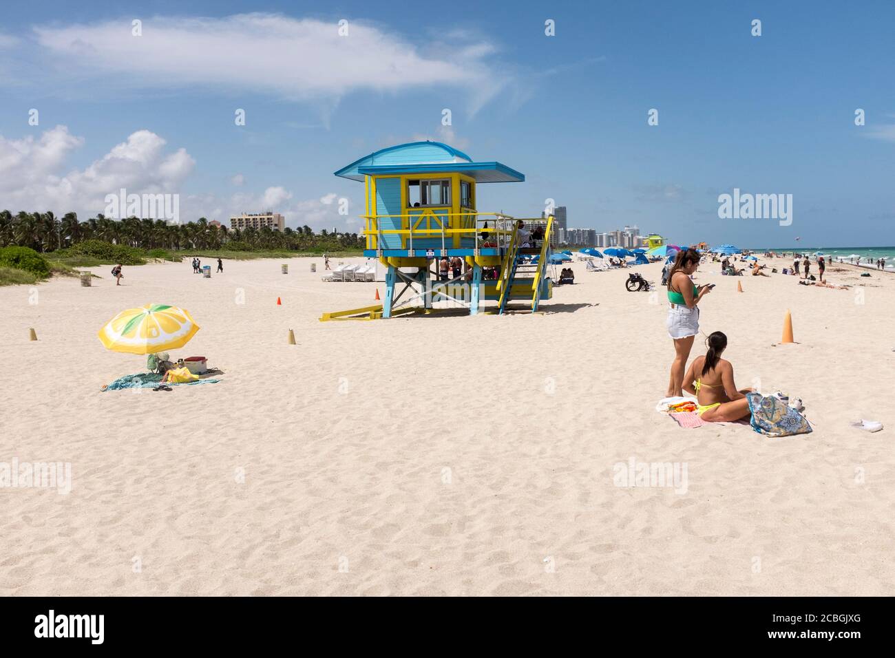 Les gens qui apprécient une journée sur la plage avec un maître nageur se tiennent en arrière-plan, à South Beach, Miami Beach, Floride, États-Unis. Banque D'Images