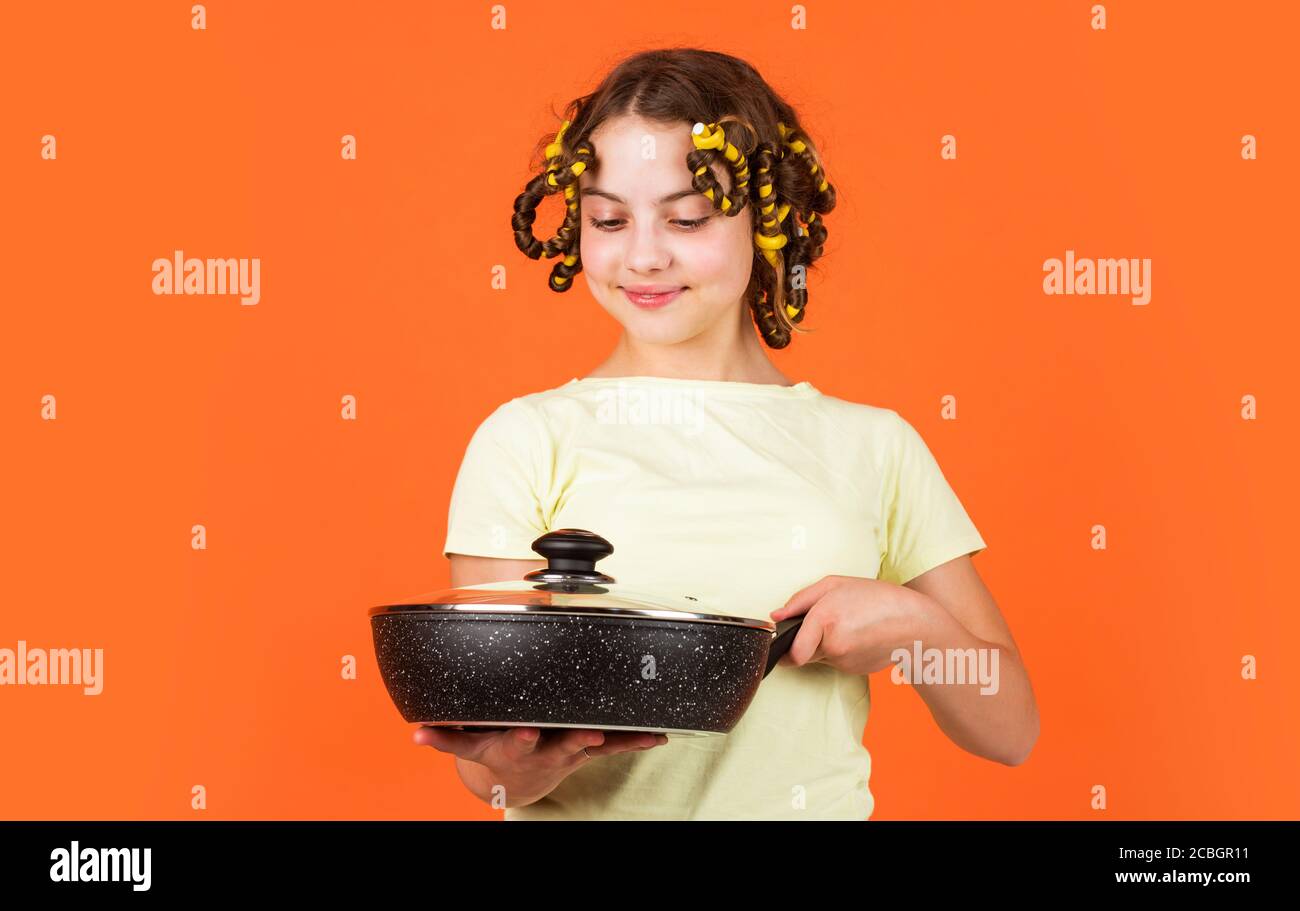 chef confiant. enfant joyeux avec des pillards. ménage de l'enfance. petite femme tient la casserole. cuisine dans la cuisine. concept de ménage. cuisine pour enfants à la maison. bonne enfance. Banque D'Images