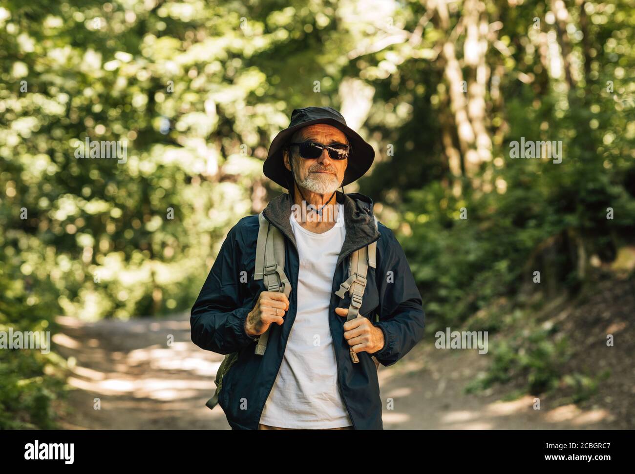 Homme senior marchant dans la forêt avec un sac à dos Banque D'Images