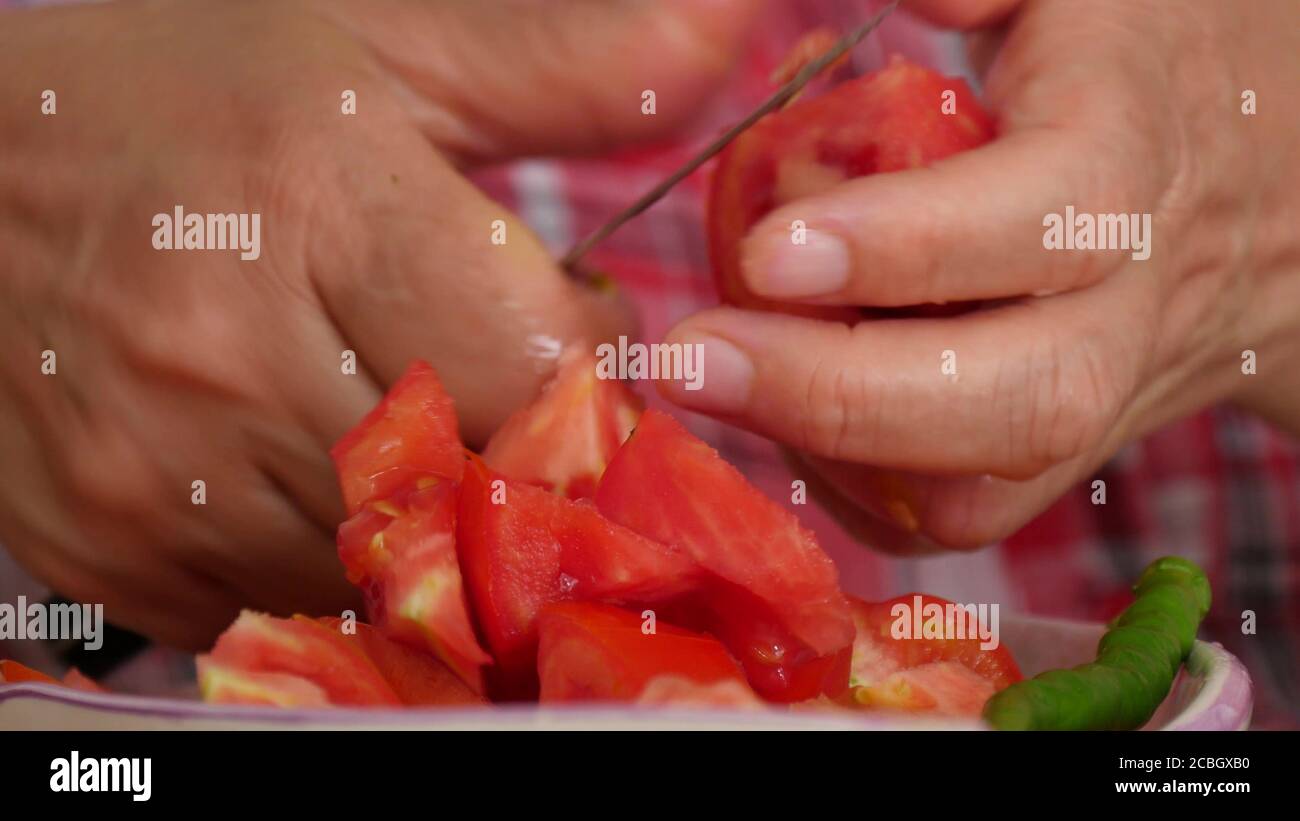 Gros plan de la femme coupant de la tomate fraîche pour cuisiner à la main Banque D'Images