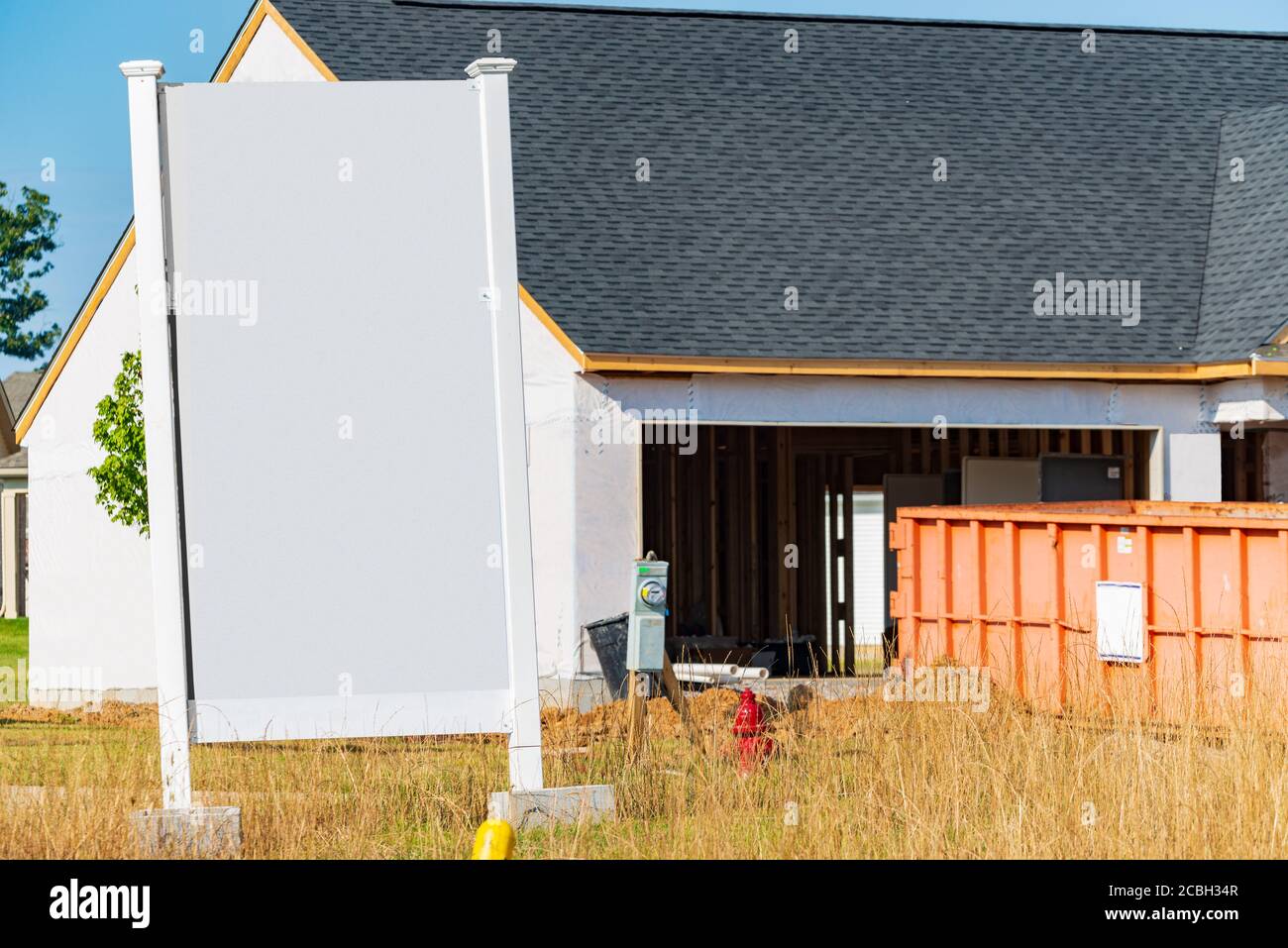 Plan horizontal d'un grand panneau blanc vierge devant une nouvelle maison en construction. Banque D'Images