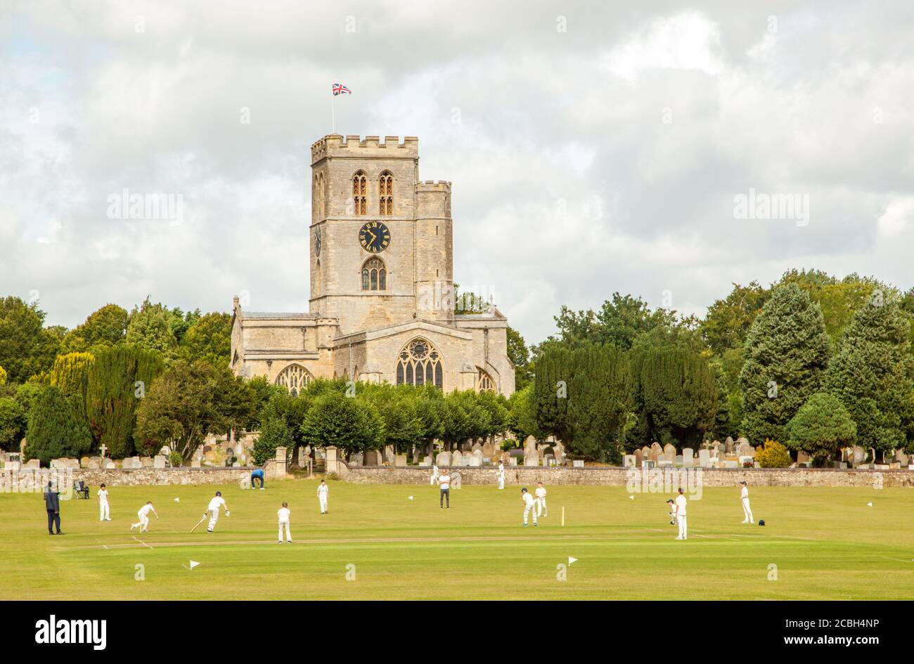 Match junior de cricket pour les jeunes sur la pittoresque prairie de l'église Stade du club de cricket de Thame, Oxfordshire, en Angleterre, avec St Mary's. église en arrière-plan Banque D'Images