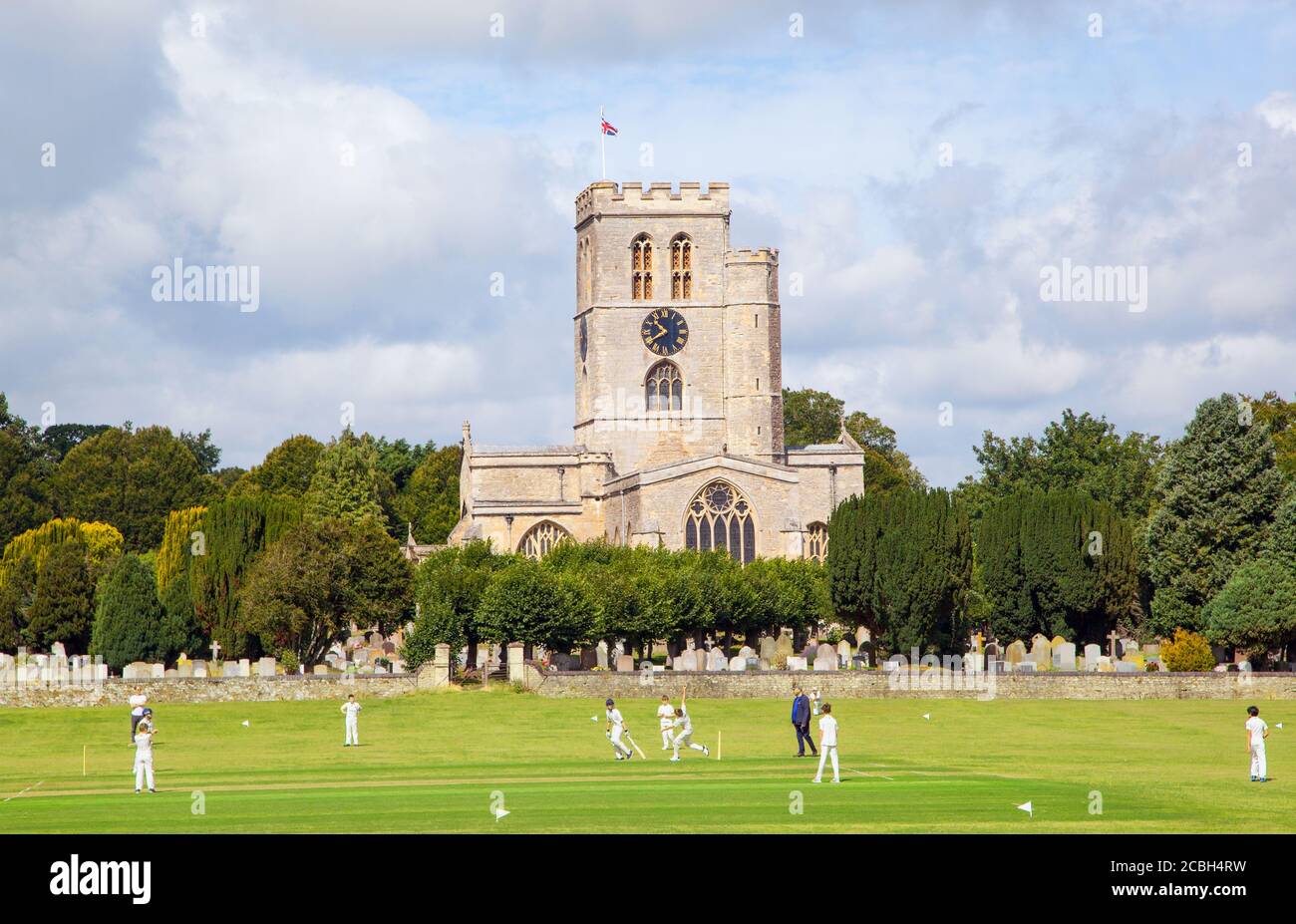 Match junior de cricket pour les jeunes sur la pittoresque prairie de l'église Stade du club de cricket de Thame, Oxfordshire, en Angleterre, avec St Mary's. église en arrière-plan Banque D'Images