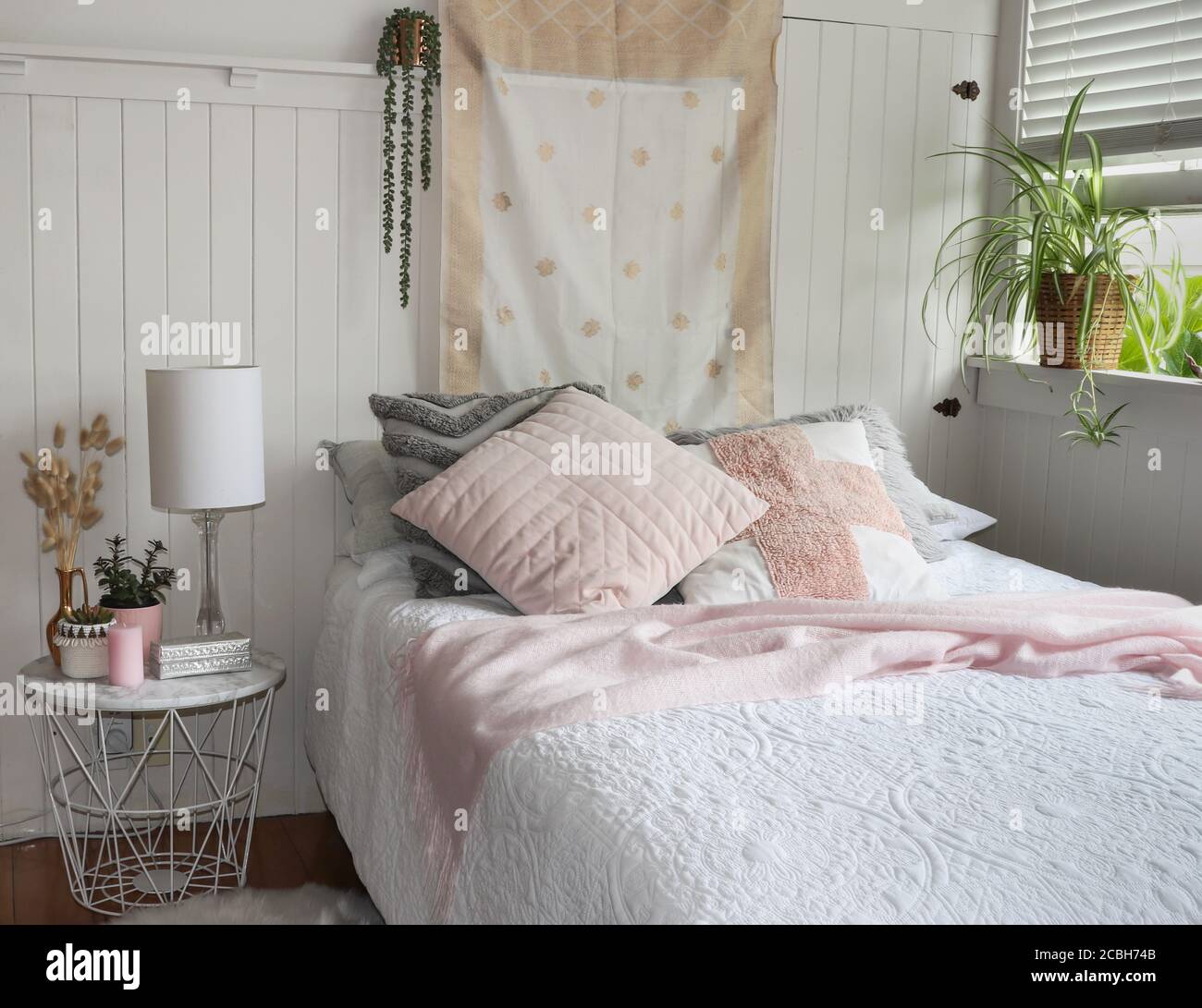 décor blanc et rose avec coussins et table de chevet Banque D'Images