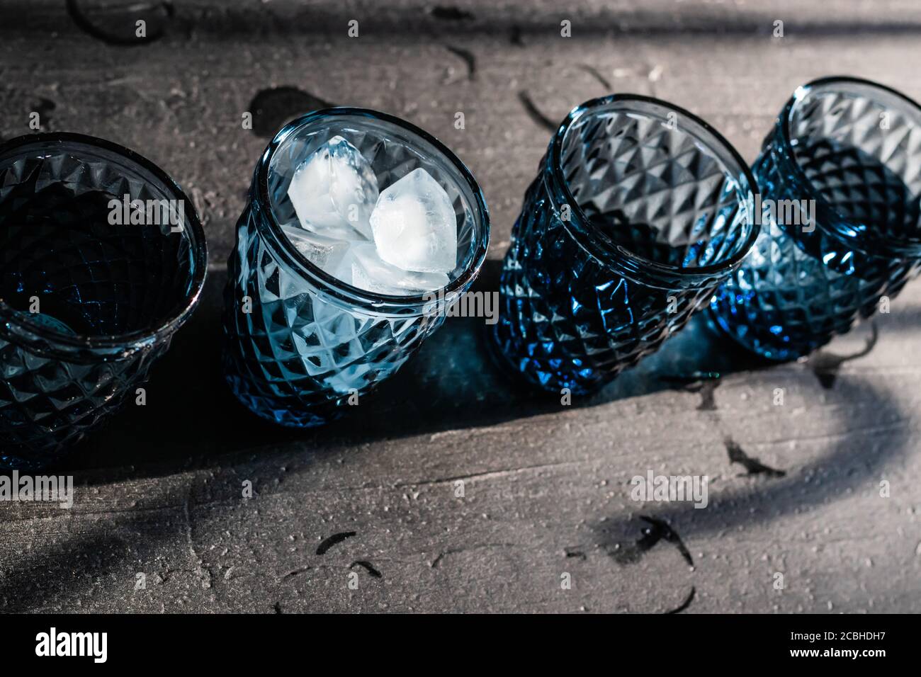 Faire une boisson froide dans un bar à la maison. Verres géométriques bleus avec glace et boisson, Banque D'Images