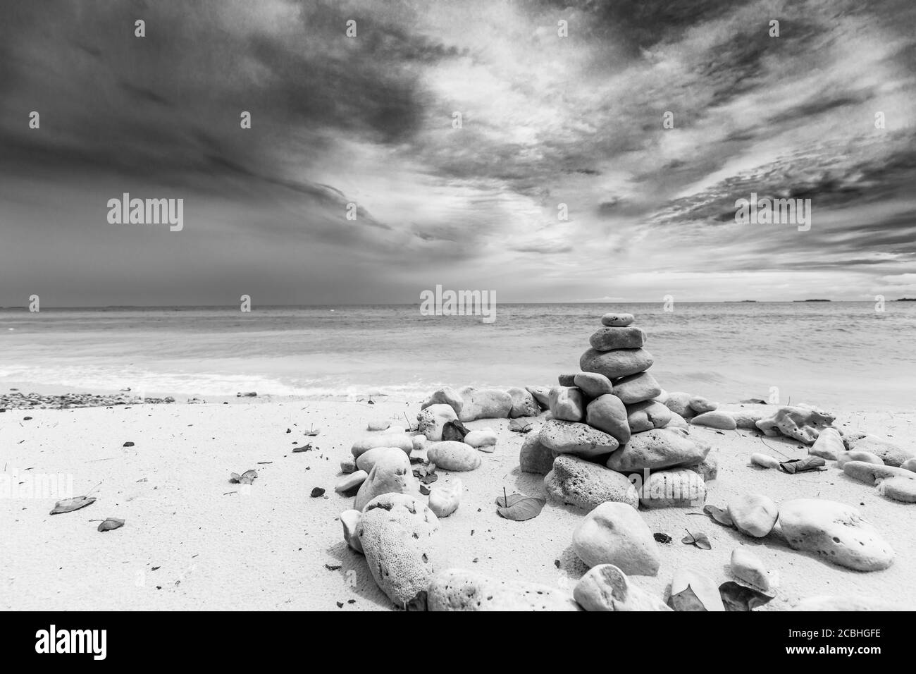 Pierres empilées sur la mer au coucher du soleil. Pierres équilibrées empilées sur une tour sur la plage, nuages avec ciel spectaculaire Banque D'Images