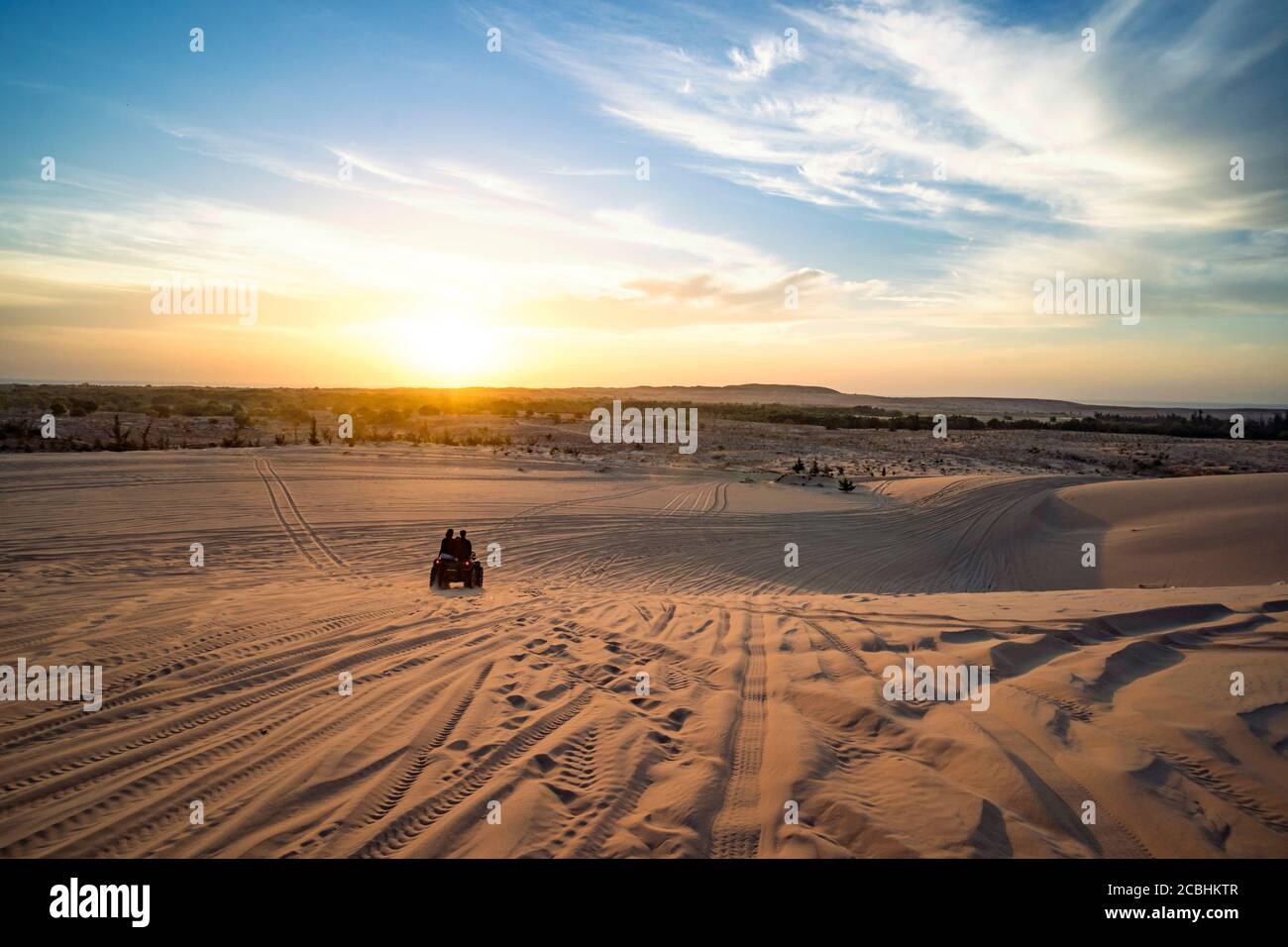 Lever du soleil dans le désert. Scène avec deux motards. Les touristes voyagent sur un tout-terrain tout-terrain à travers les dunes de sable du désert vietnamien. Safari tôt dans le Banque D'Images