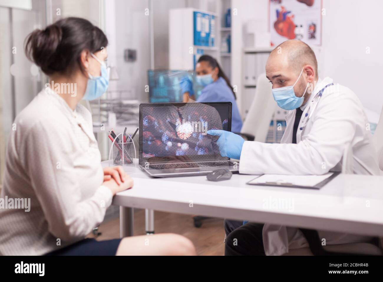 Médecin expliquant les symptômes du covid 19 à une jeune patiente dans le bureau de l'hôpital pendant l'examen. Banque D'Images Médecin expliquant les symptômes du covid 19 à une jeune patiente dans le bureau de l'hôpital pendant l'examen. Banque D'Images