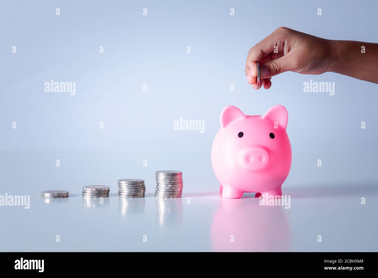 Main de l'enfant tenant la pièce mise dans la banque de piggy avec la pile d'argent croissance économiser de l'argent, concept d'investissement pour le plan de liberté financière, affaires. Banque D'Images