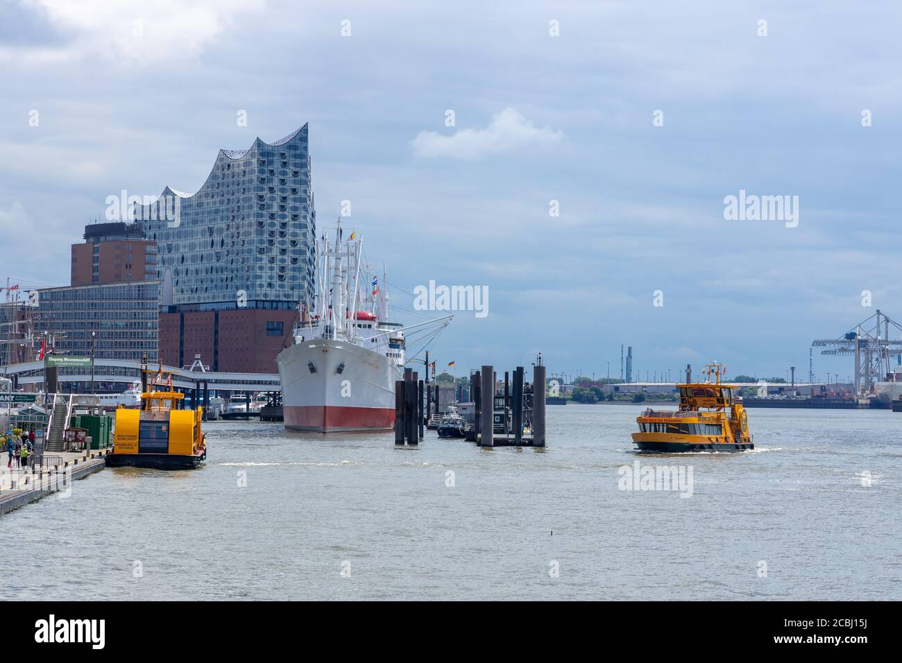 Hambourg, Allemagne - 8 juin 2020 : salle philharmonique d'Elbe dans la ville de hafen, au bord de l'elbe. Un ferry traverse la rivière à l'avant. Banque D'Images