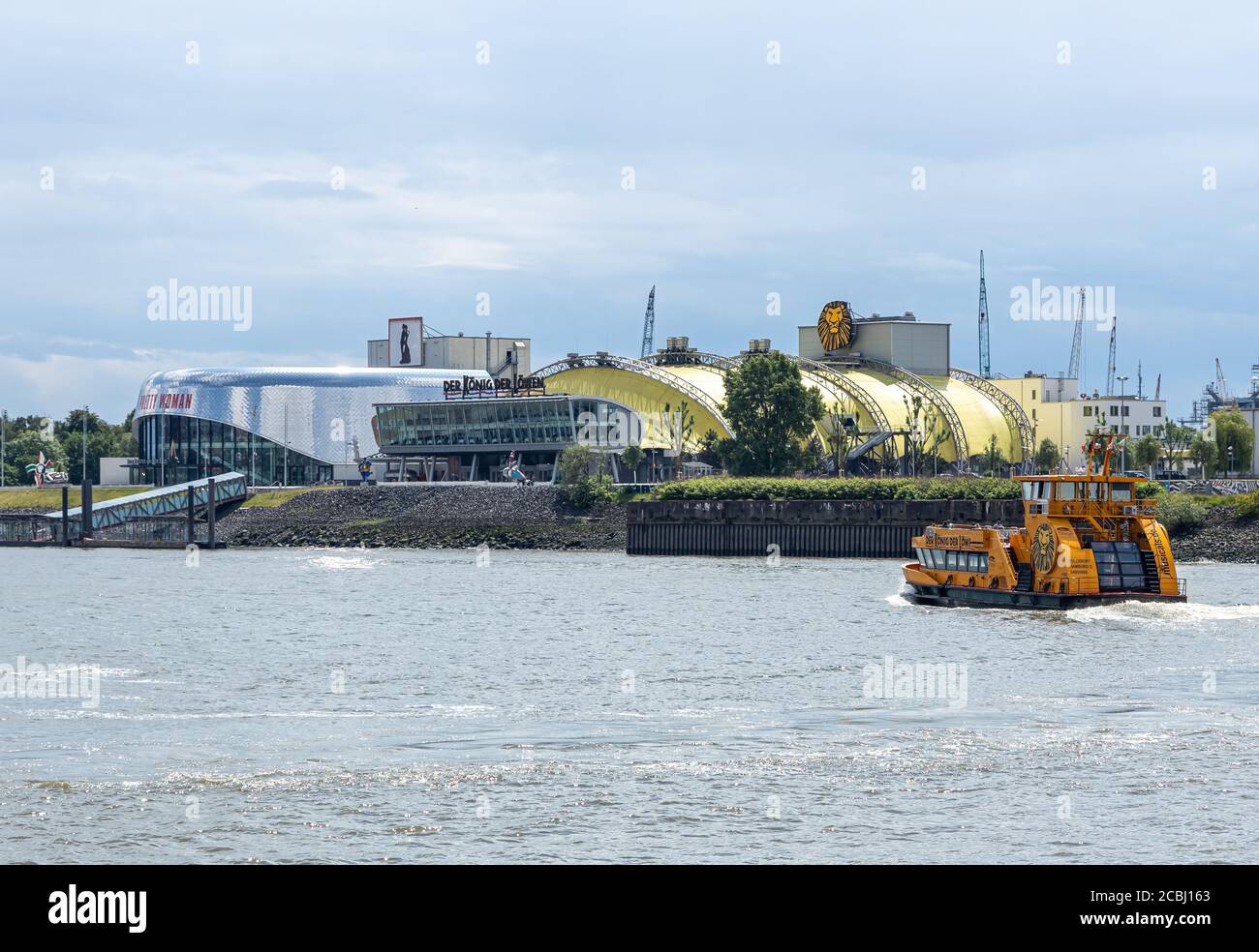 Hambourg, Allemagne - 8 juin 2020 : le théâtre de divertissement de l'autre côté du Landungsbruecken. Un ferry traverse la rivière elbe. Banque D'Images