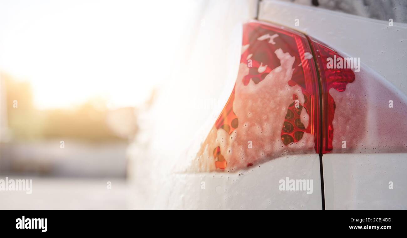Phare arrière de voiture recouvert de mousse lors du lavage de voiture, gros plan Banque D'Images