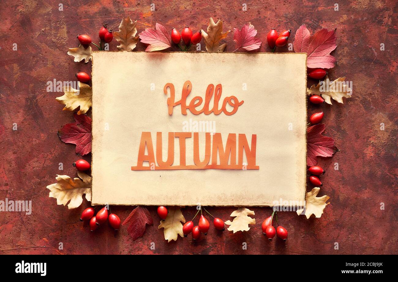Papier artisanal, texte Hallo automne sur page papier vieilli. Cadre d'automne rouge foncé et brun avec bordure décorative à partir de feuilles d'automne en chêne. Banque D'Images